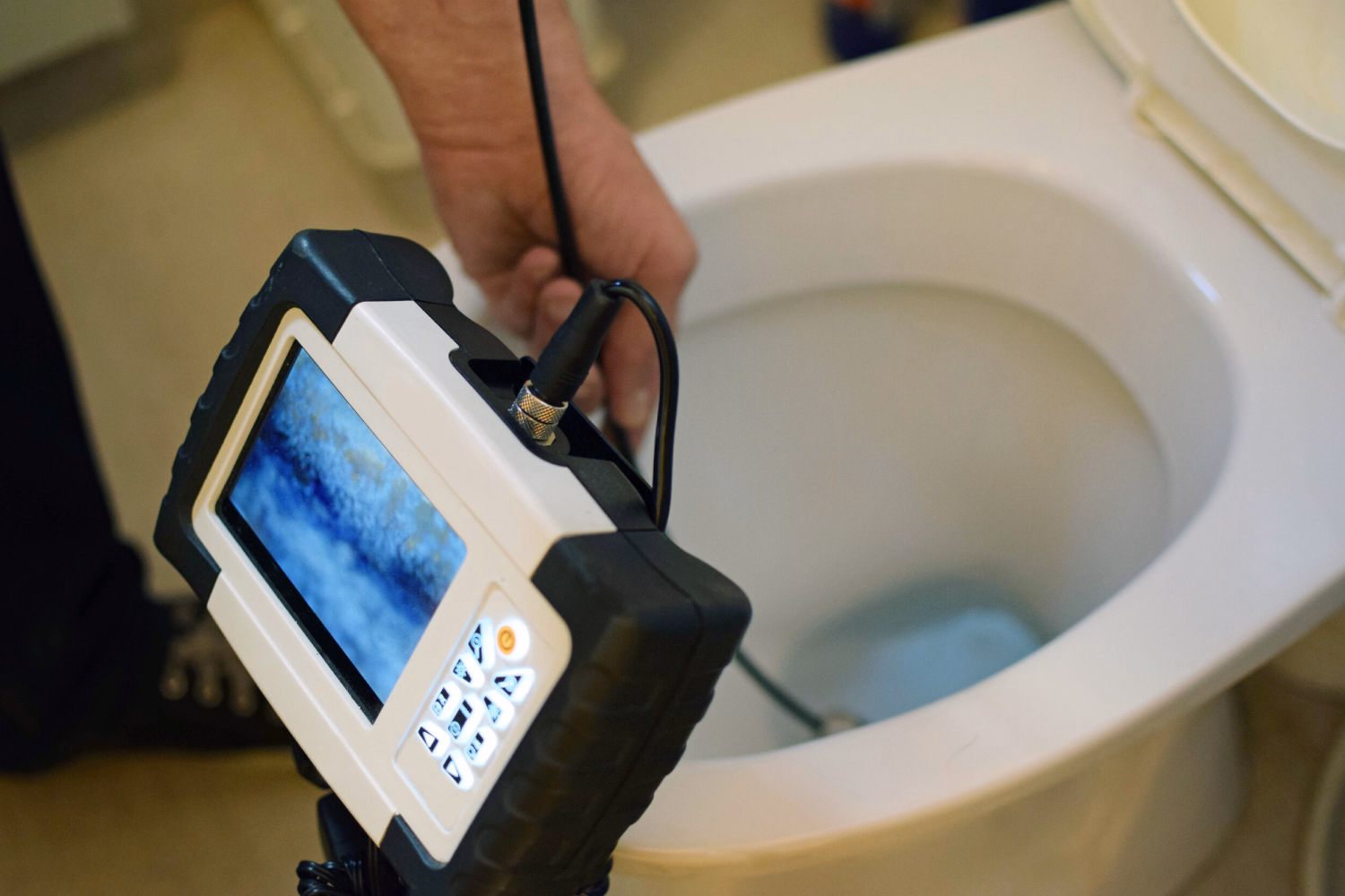 Engineer clearing toilet blockage with heavy-duty auger